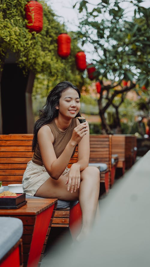 Young Woman Sitting at an Outdoor Restaurant and Eating Ice Cream 