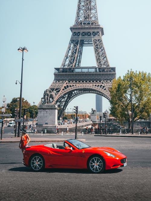 Woman standing by Ferrari at the Eiffel tower