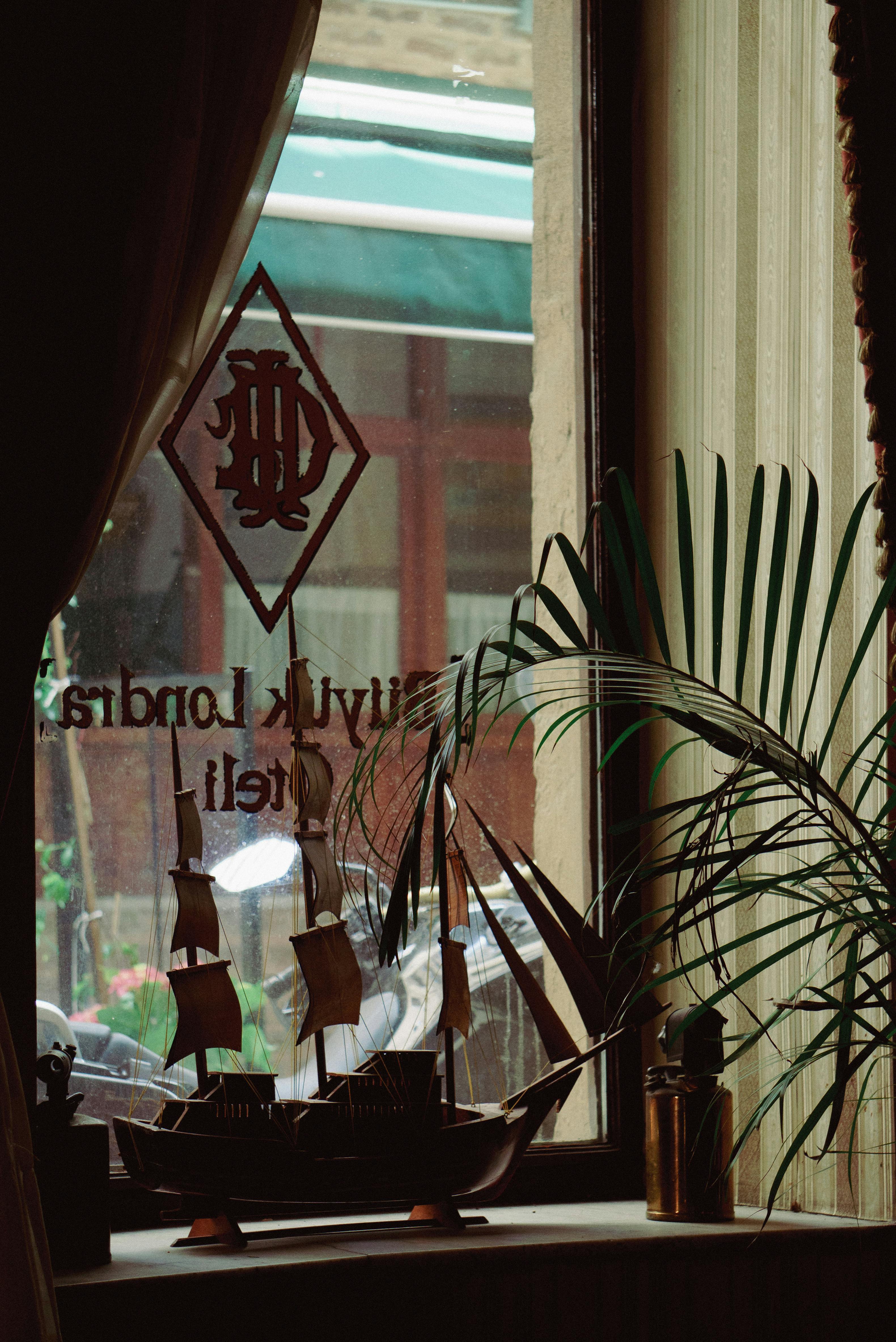 Free Warm interior with a model ship by a window and leafy plants, creating a serene atmosphere. Stock Photo