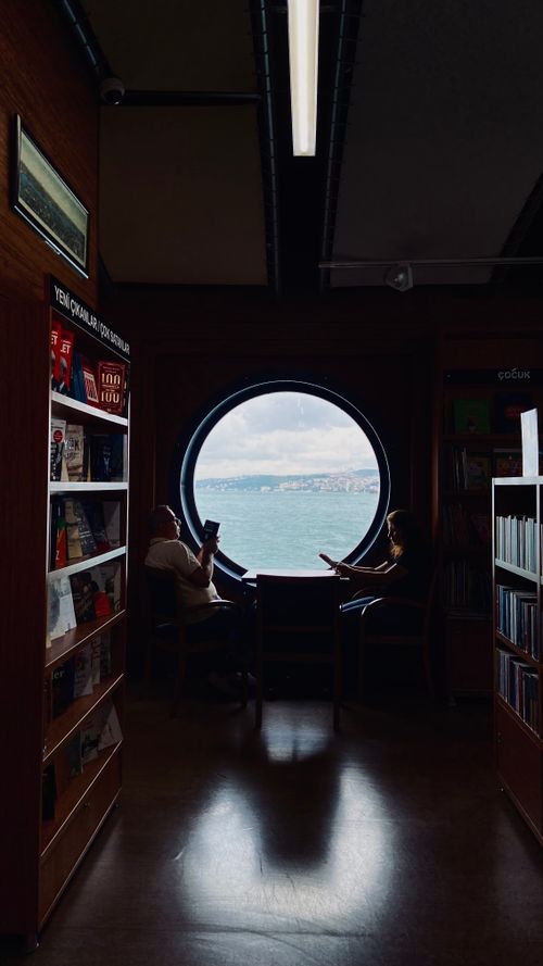 Free Enjoy a tranquil reading spot with a stunning round window view of the sea. Stock Photo