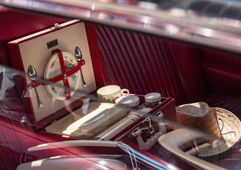 Close-up of a vintage picnic set inside a car with decorative plates and silverware.
