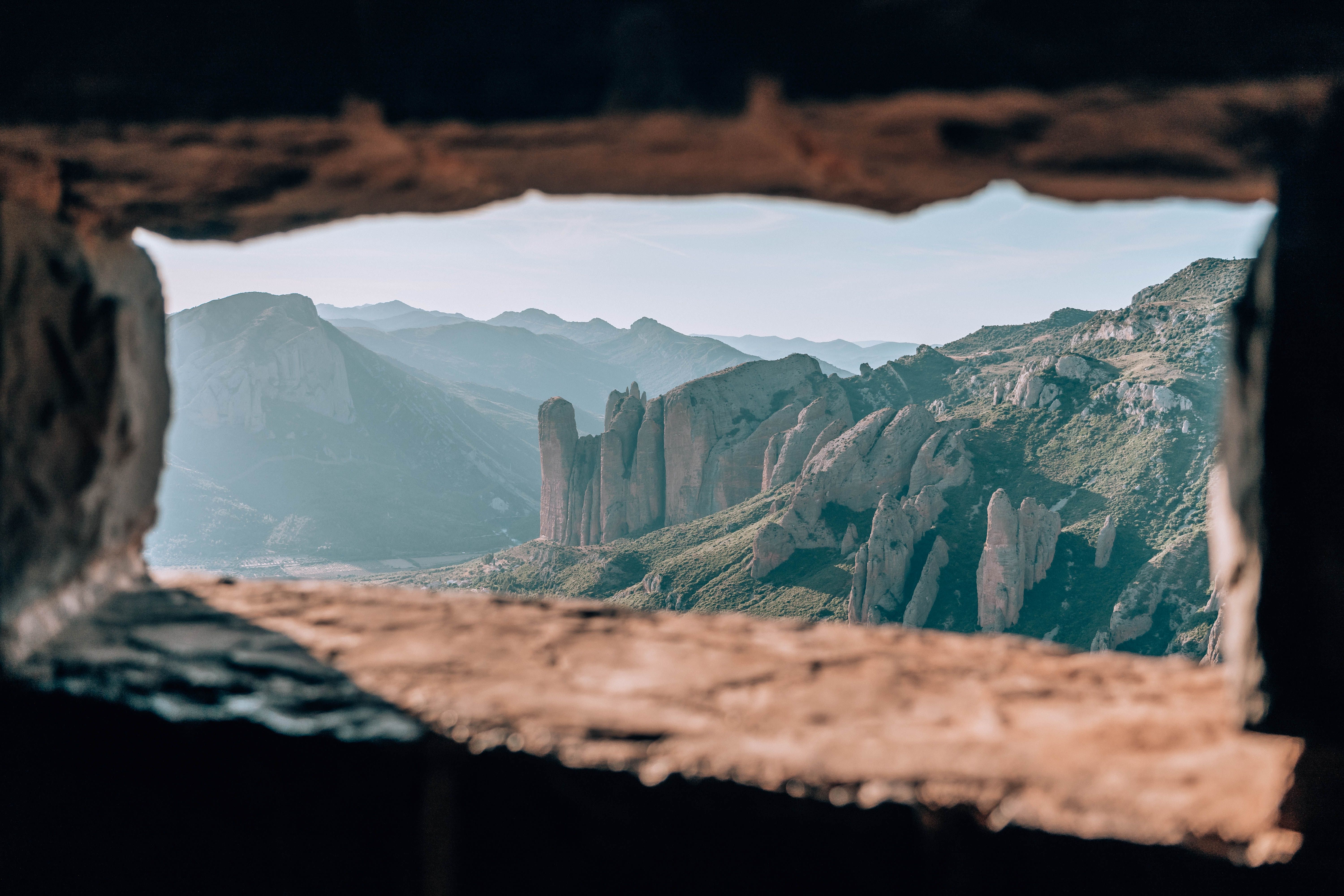 Dramatic rock formations of Mallos de Riglos in Spain, captured through a rustic window.