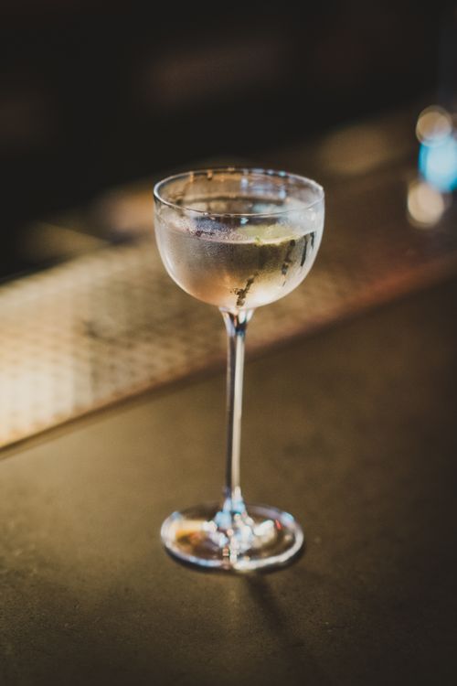 Free Close-up of a refined cocktail glass on a dimly lit bar counter. Stock Photo