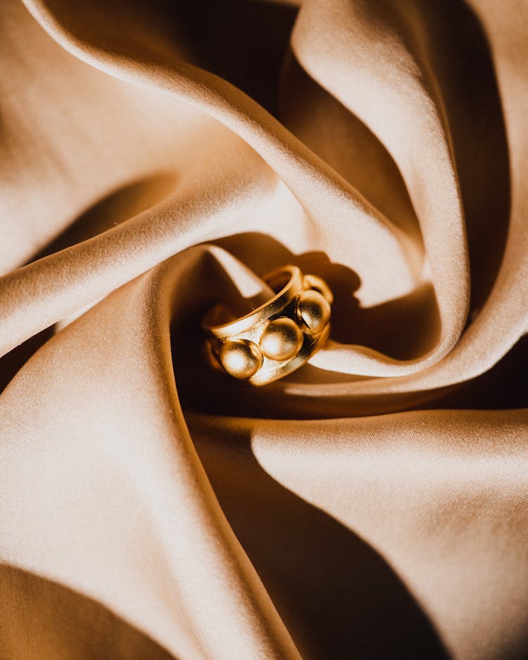 Photo Of A Golden Earring On A Draped Fabric