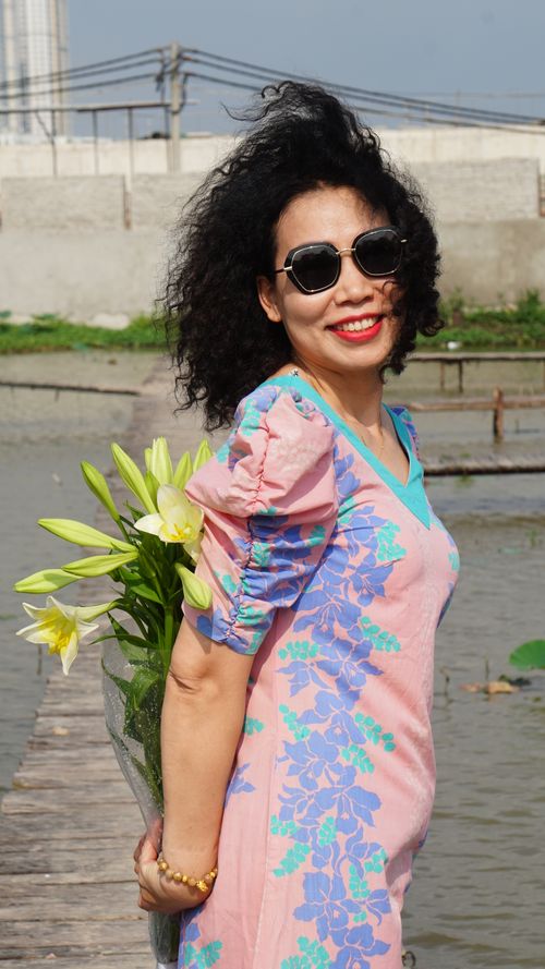Free A fashionable woman with sunglasses and flowers poses outdoors, radiating joy and style. Stock Photo