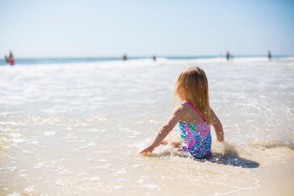 A young girl playing joyfully in the ocean waves on a bright summer day.