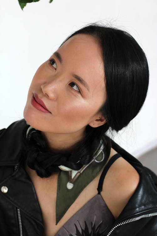 Photo of a Young Brunette in a Leather Jacket Looking Up and Smiling 