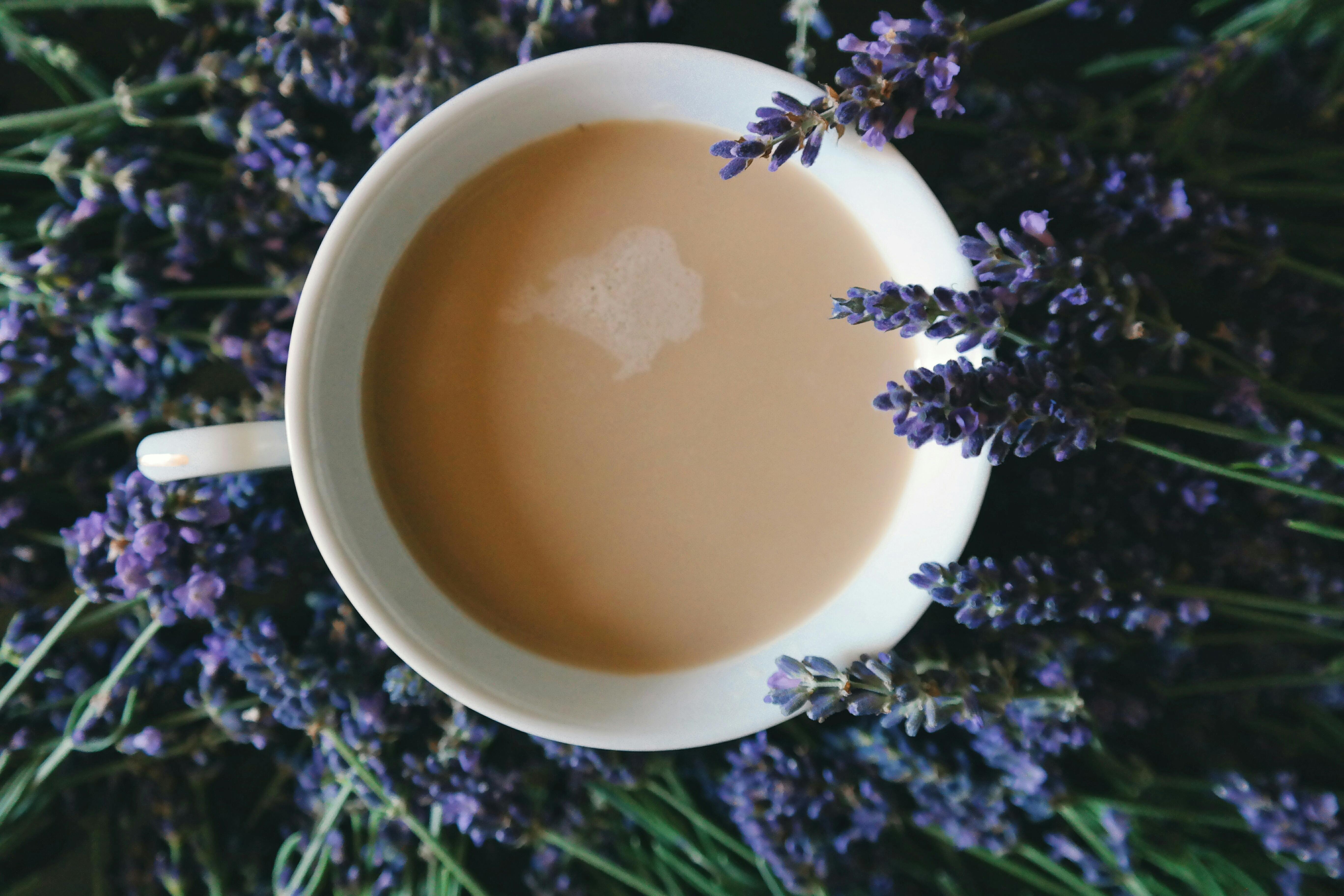 coffee filled on mug surrounded by purple flowers