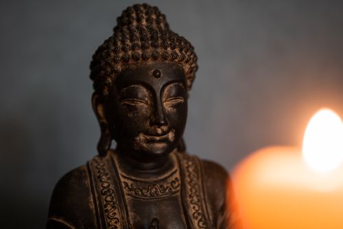 Free Close-up of a bronze Buddha statue with calming candlelight, reflecting tranquility and spirituality. Stock Photo