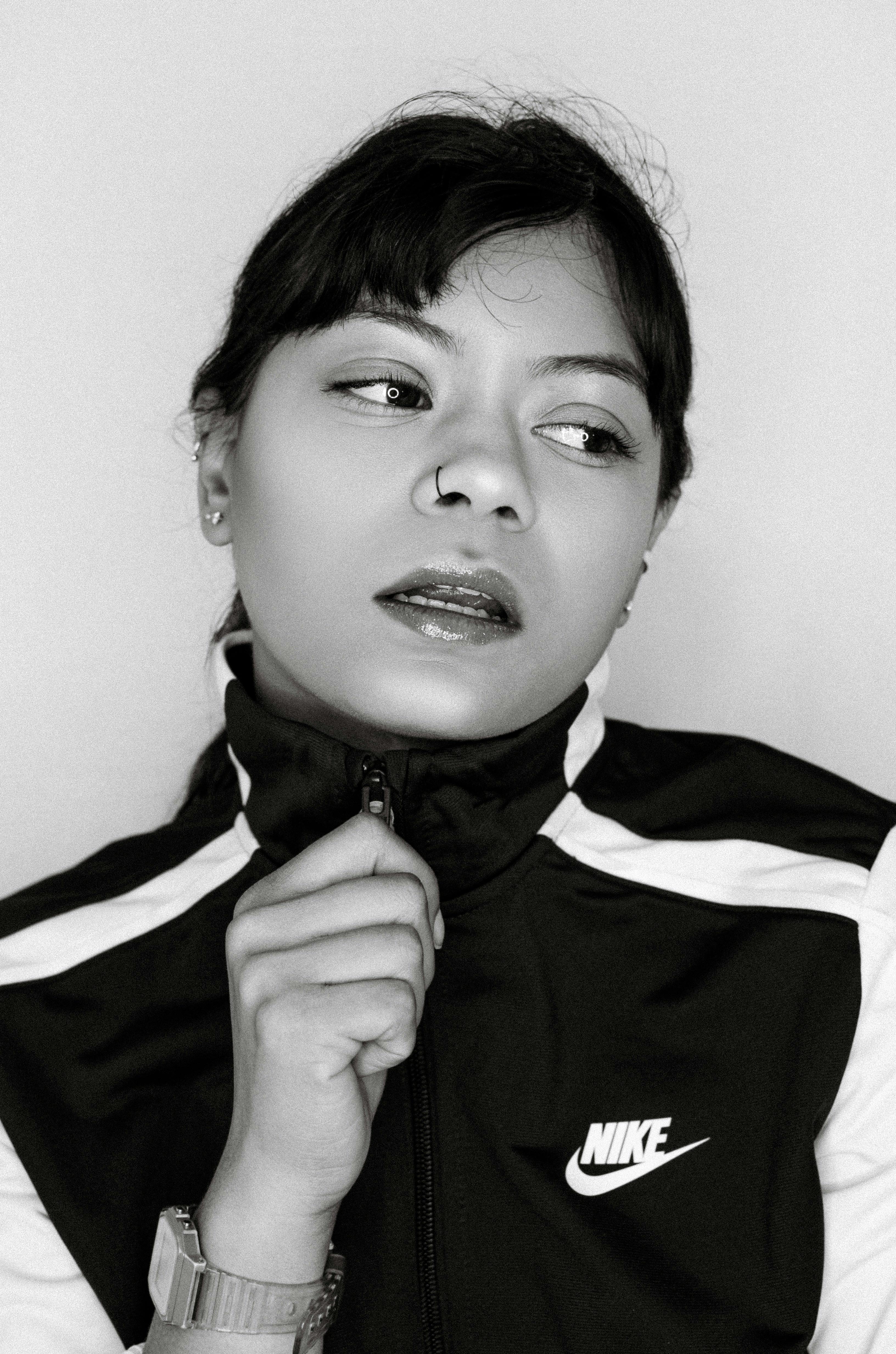 Black and white portrait of a young woman posing in a sporty jacket, exuding confidence.