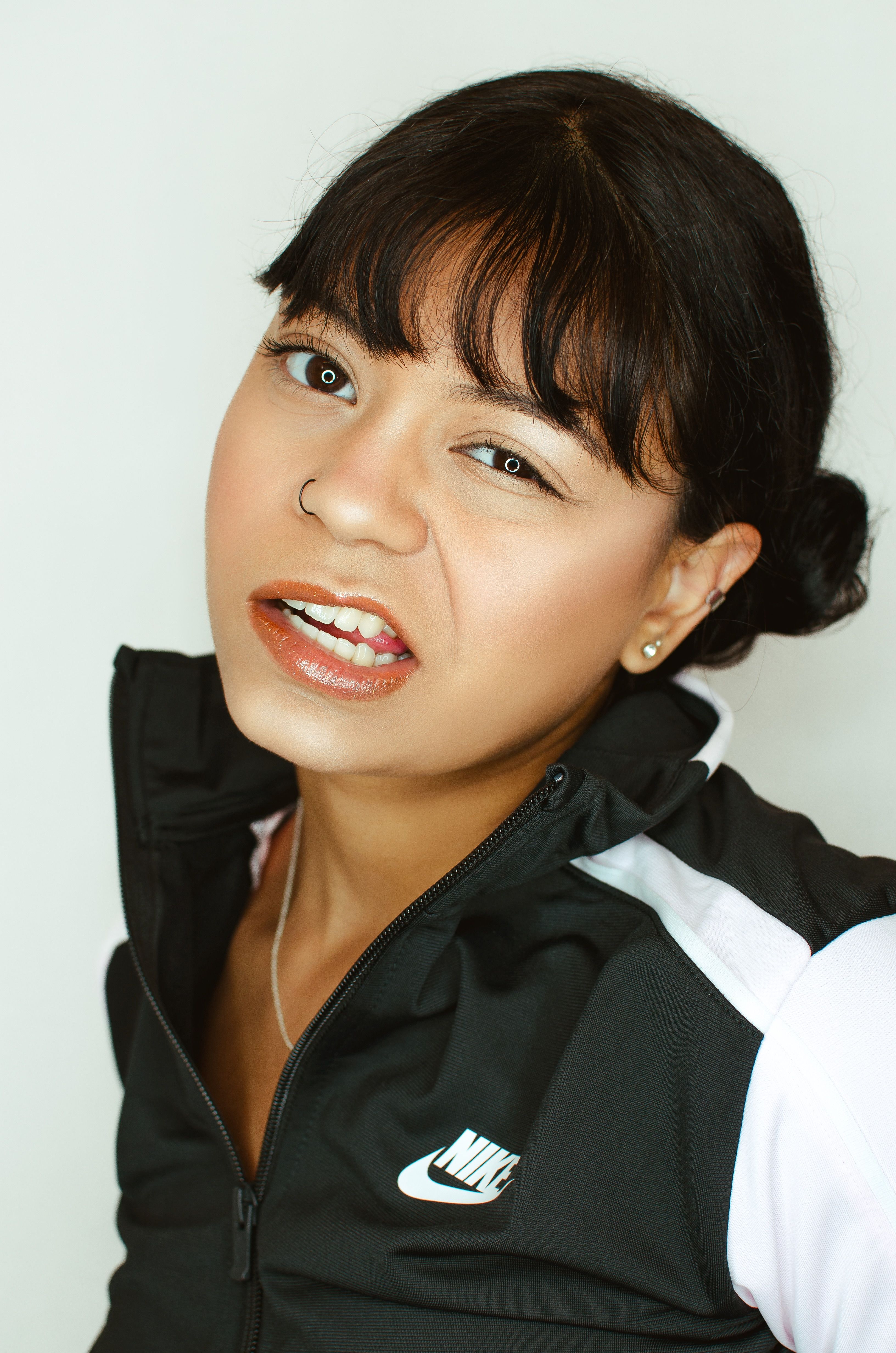 Portrait of a woman with black hair wearing sportswear on a white background.