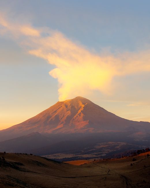 Breathtaking sunset over the Popocatépetl Volcano in Mexico emitting smoke, capturing its serene majesty.