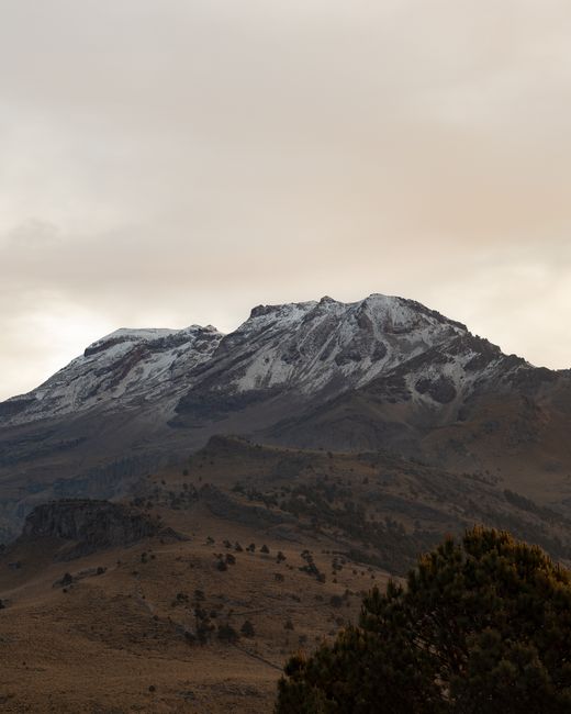 A rugged, snow-capped mountain range under a cloudy sky, showcasing nature's tranquility.