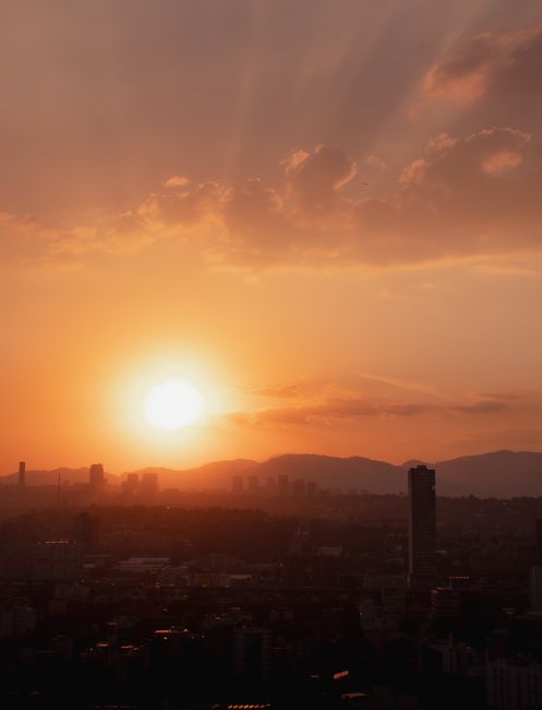 Captivating sunrise over Mexico City skyline with a warm, dramatic sky.