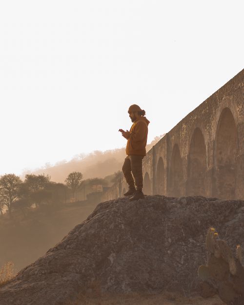 Free A person enjoys a serene sunset next to a historic aqueduct, capturing the beauty of nature and architecture. Stock Photo
