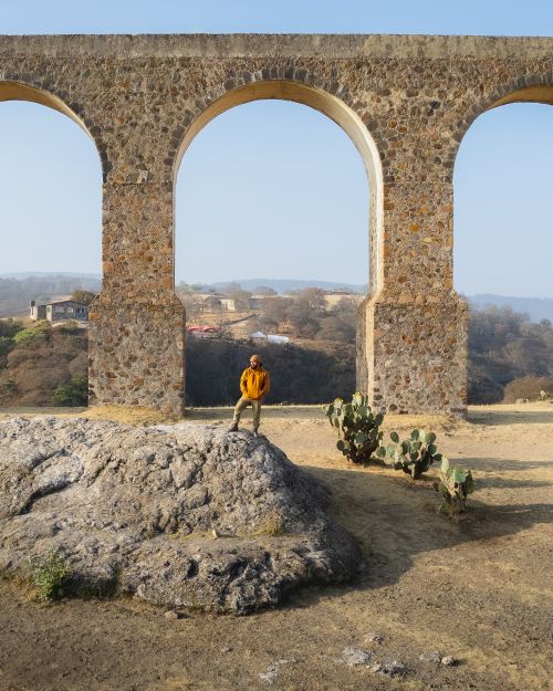 Free A scenic view of a man standing by an ancient stone aqueduct in nature. Stock Photo