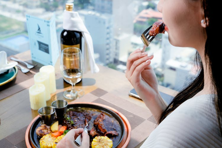 Woman Eating Dinner With Wine At Restaurant