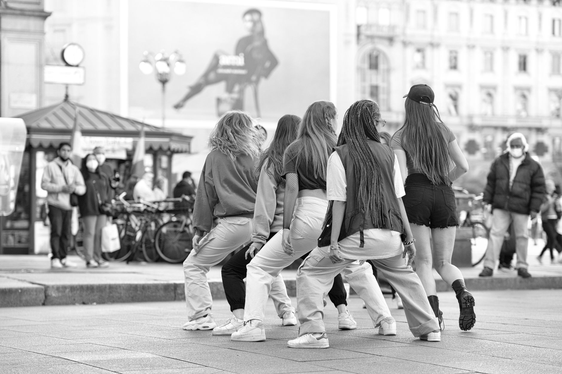 Black and white photo of dancers performing in a bustling Milan city square.