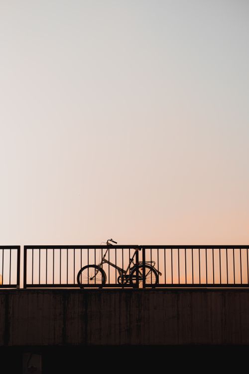 Free Silhouette of a bicycle on a bridge with a clear evening sky. Stock Photo