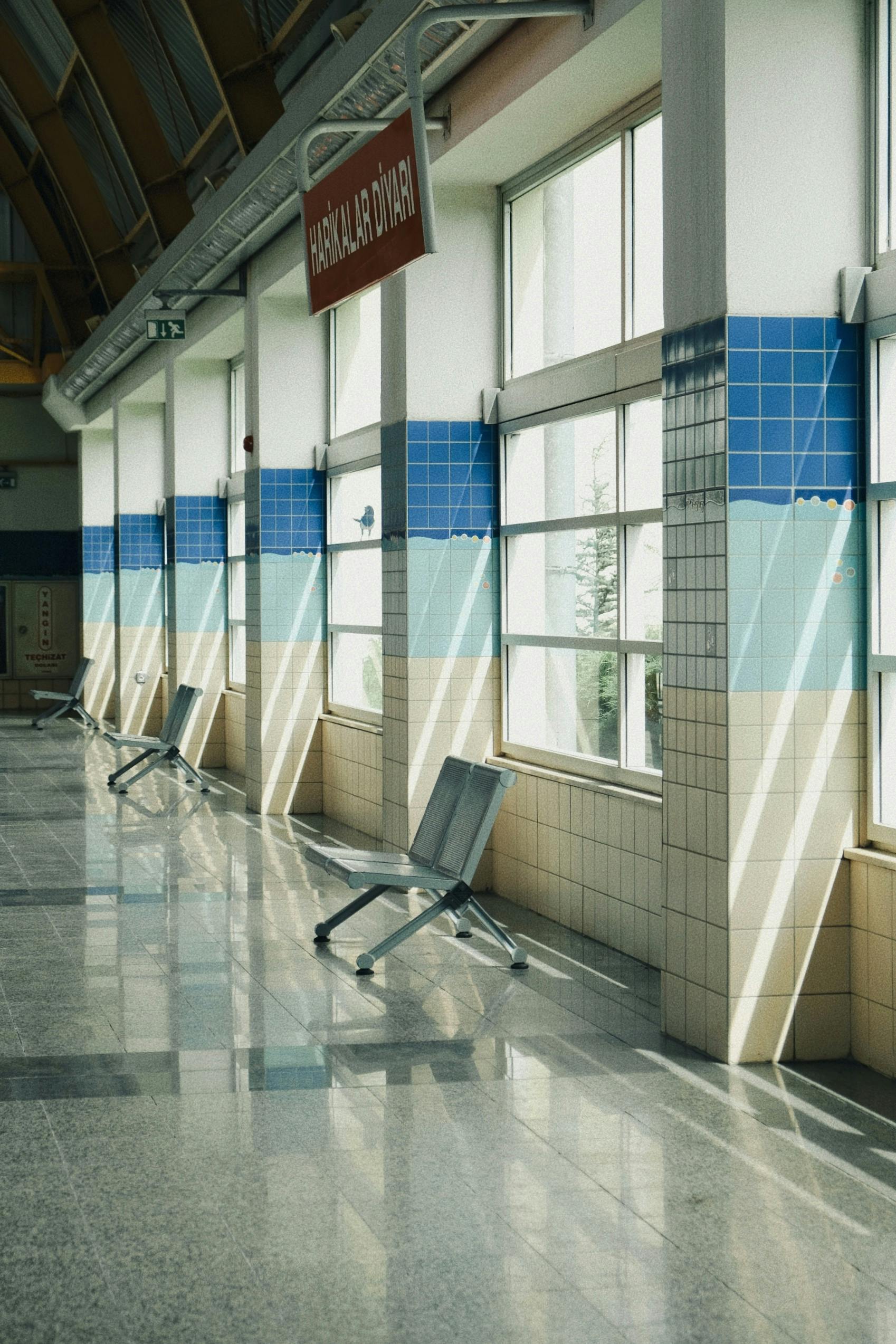 Bright indoor corridor featuring blue tiles and sunlight streaming through windows.