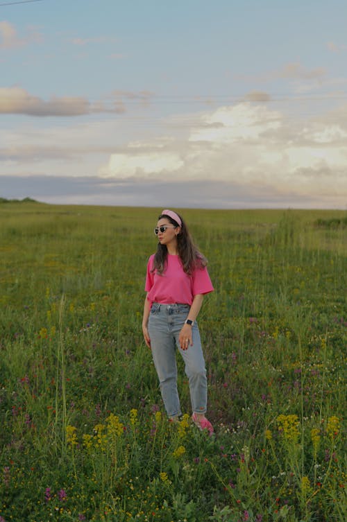 Young Woman in a Casual Outfit Standing on a Grass Field in Summer
