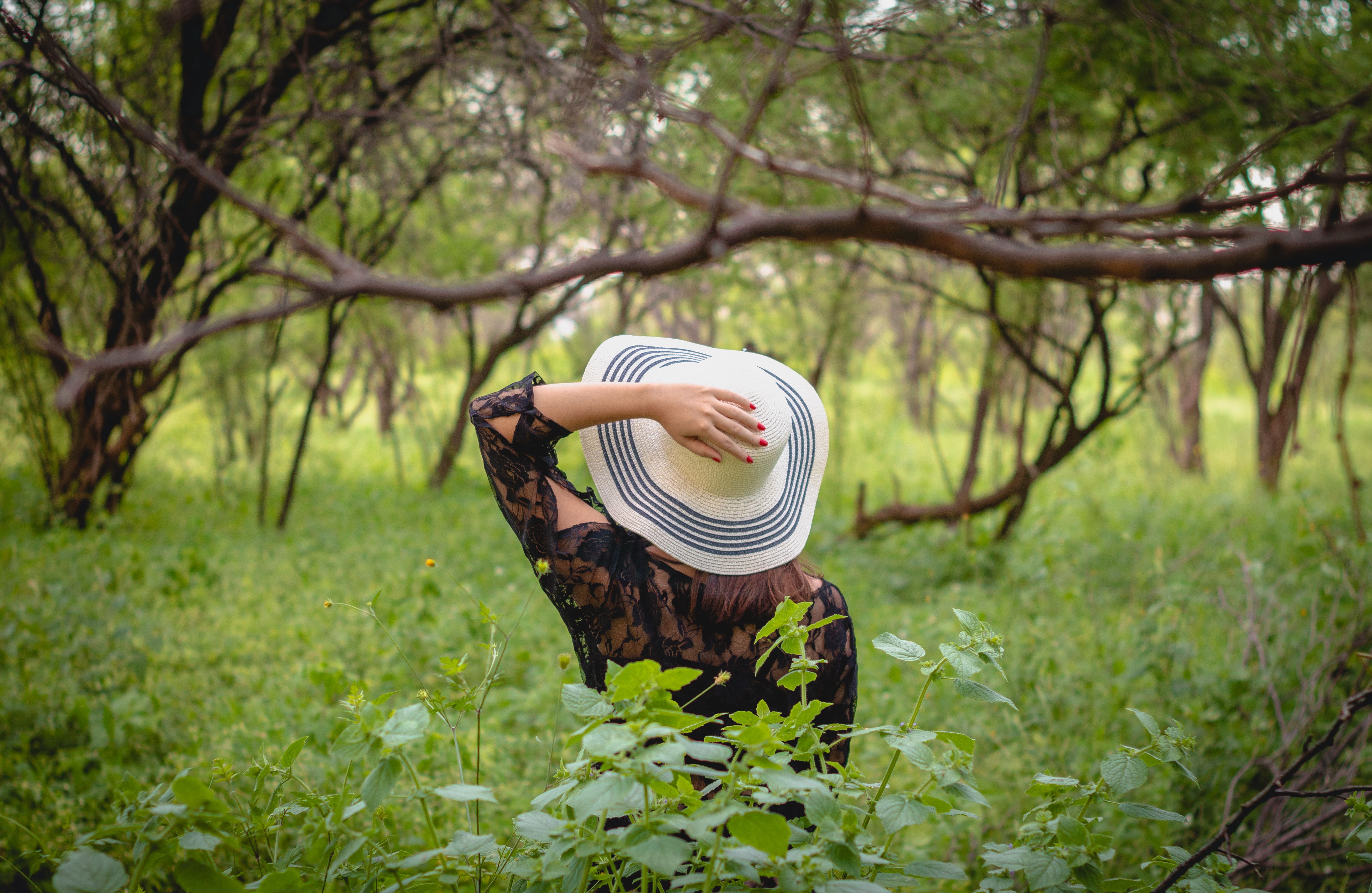 A woman stands in a serene forest in Aracati, Brazil, wearing a wide-brimmed hat.