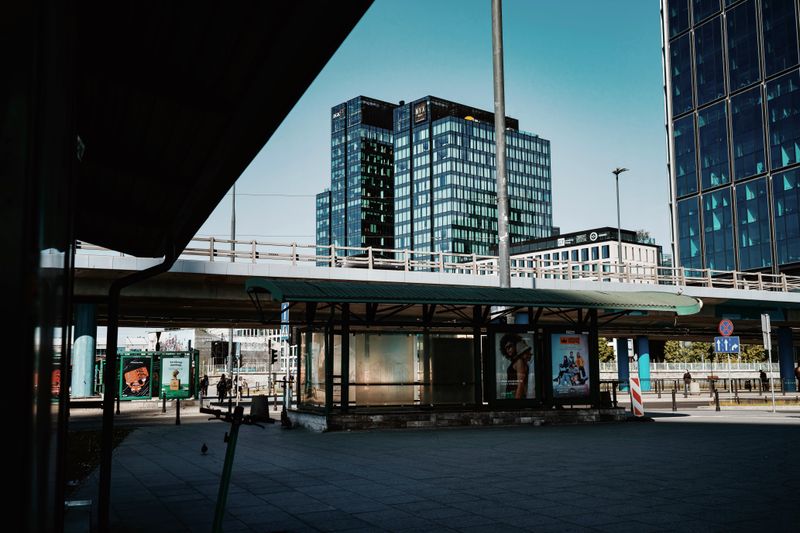 Contemporary tram station in urban Warsaw with skyscrapers and transportation infrastructure.