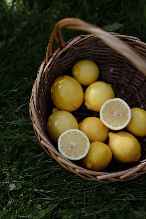 Free A wicker basket filled with fresh yellow lemons on a lush green grass background. Stock Photo