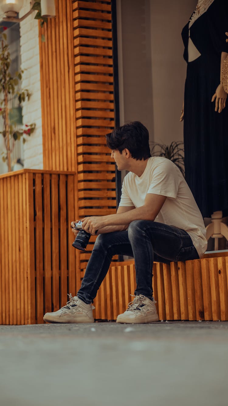 Candid Picture Of A Man With A Camera Sitting Outside 