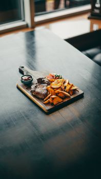A gourmet steak dinner served with roasted potatoes and vegetables on a cutting board.