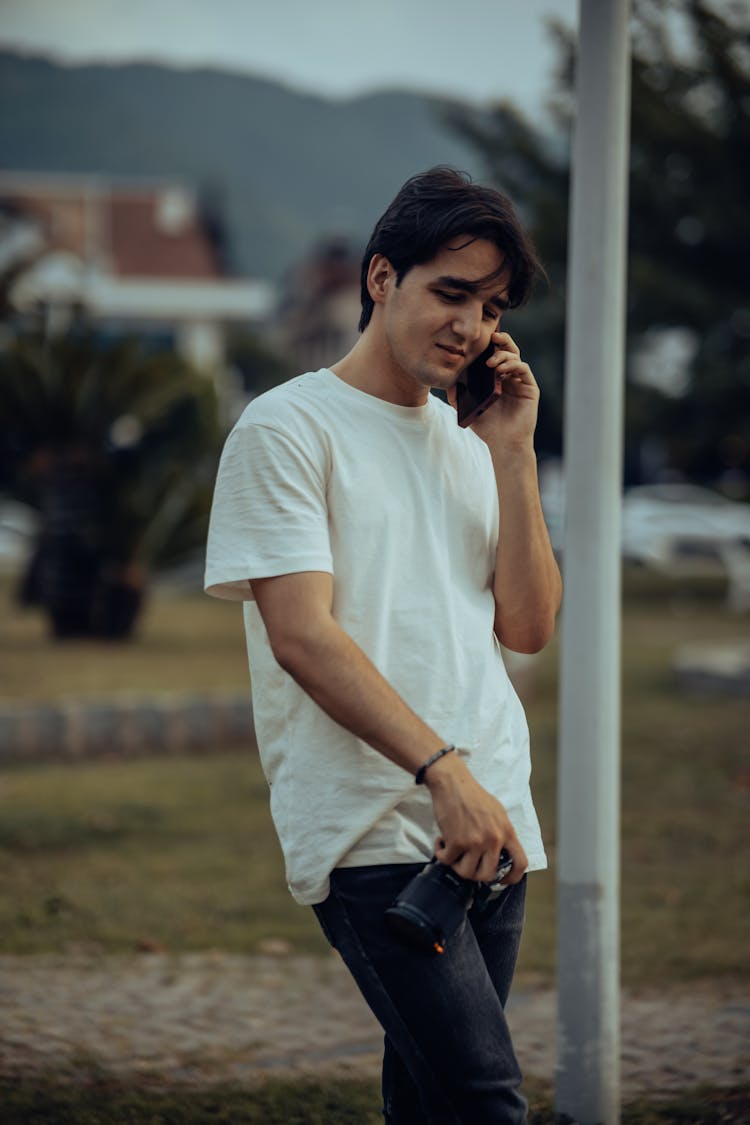 Young Man Holding A Camera And Talking On The Phone