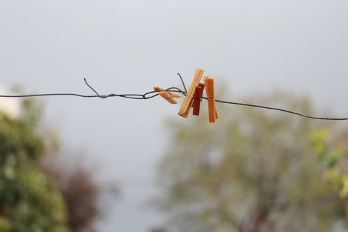 Free A pair of wooden clothespins on a wire with a blurred natural background. Stock Photo