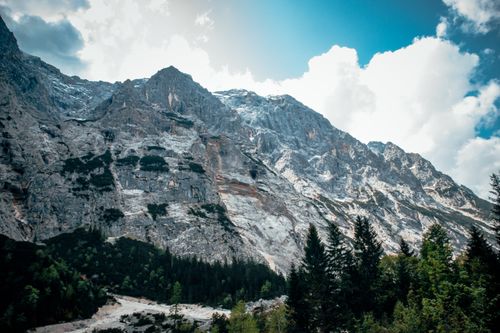 Free Breathtaking view of a snow-capped mountain range with lush green forest below. Stock Photo