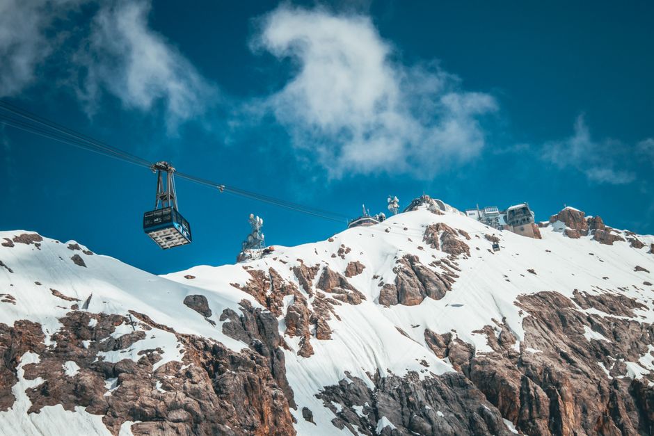 Cable car ascends over snow-covered mountains in a stunning winter landscape.