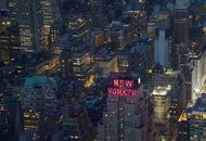 A captivating aerial shot of New York City featuring the illuminated New Yorker Hotel.