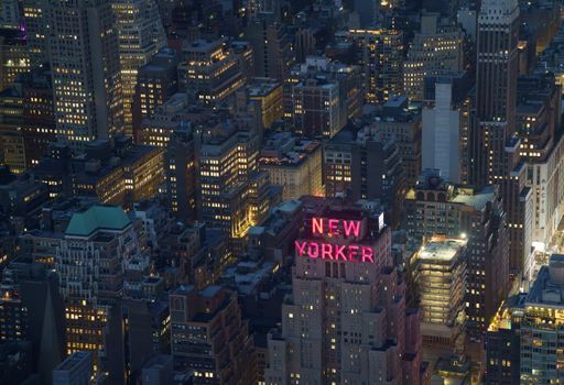 A captivating aerial shot of New York City featuring the illuminated New Yorker Hotel.