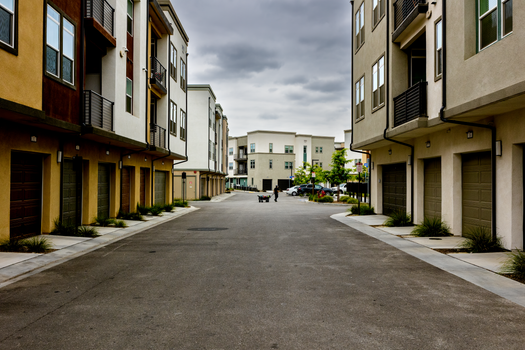 Photo by David Brown A man pulls a cart down a quiet residential street lined with modern townhouses.
