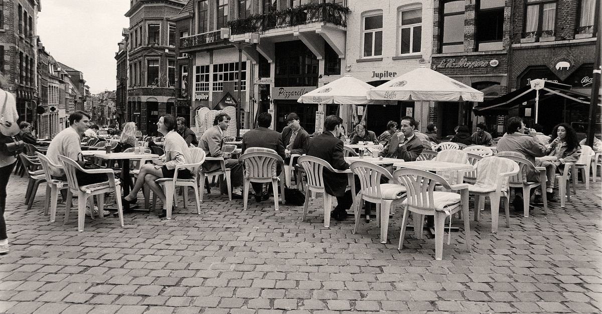 people laughing at an outdoor cafe table in a city square