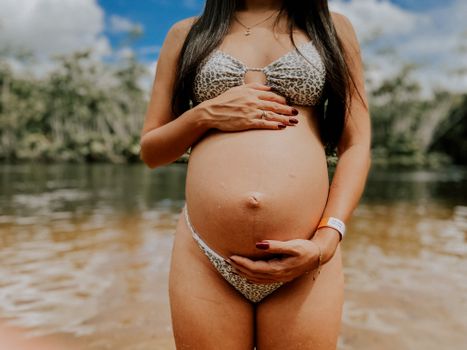 Pregnant Woman in a Bikini Holding Her Belly 