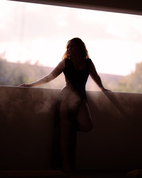 Silhouette of a Woman in a Dress Standing on a Balcony 