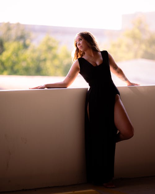 Young Woman in a Black Dress Standing on a Balcony 