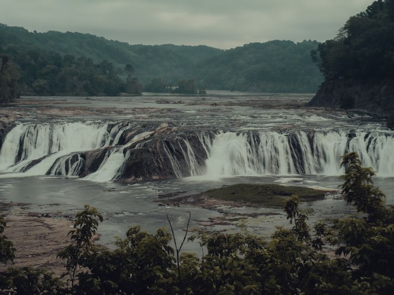 A wide waterfall cascading through lush green forest