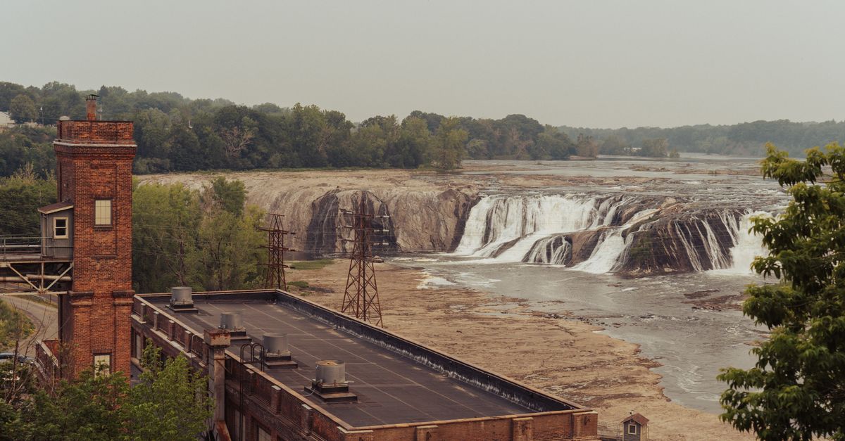 A historical mill stands against a backdrop of majestic cascading waterfalls, capturing nature and architecture.
