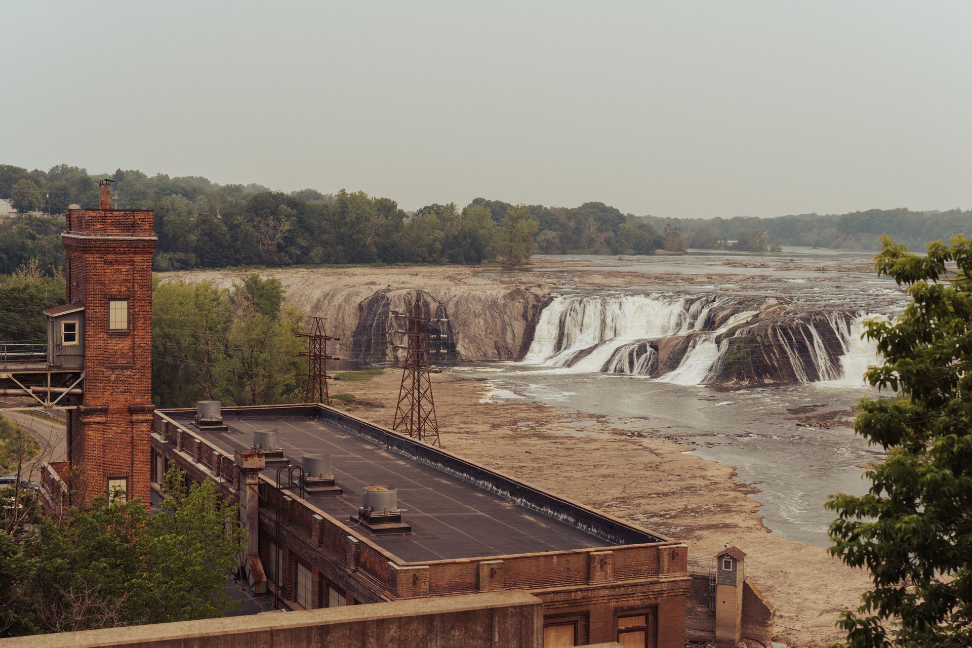 A historical mill stands against a backdrop of majestic cascading waterfalls, capturing nature and architecture.