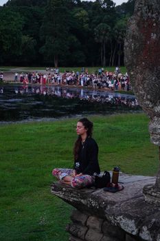Serene meditation at a park lake with calm, reflective water and lush greenery.