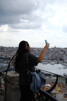 Young woman capturing a selfie with a smartphone at a scenic viewpoint in Istanbul.