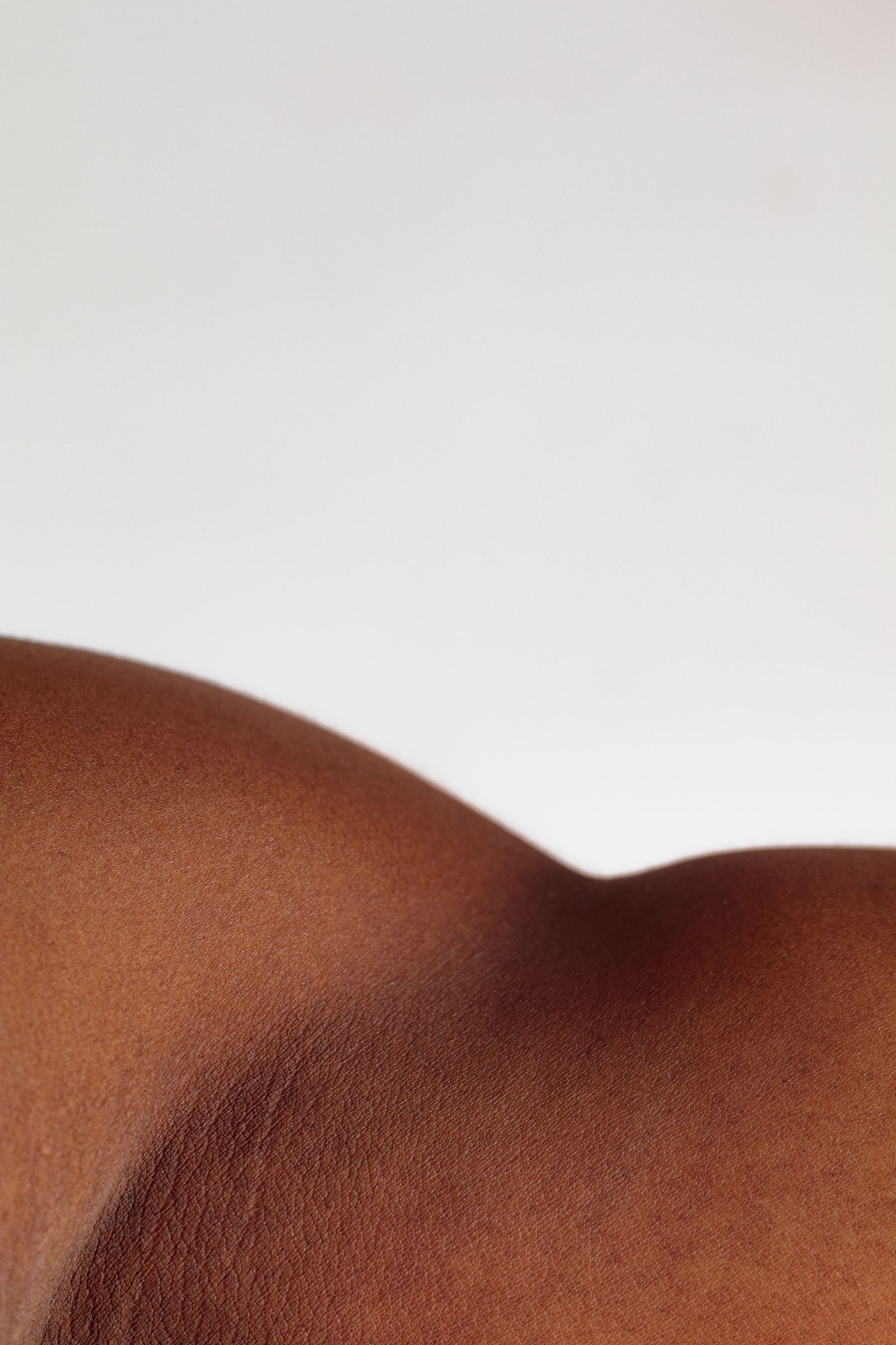 A close-up of richly pigmented skin in soft light. Skin cancer can look different on dark skin and is often found late, so regular self-checks matter.