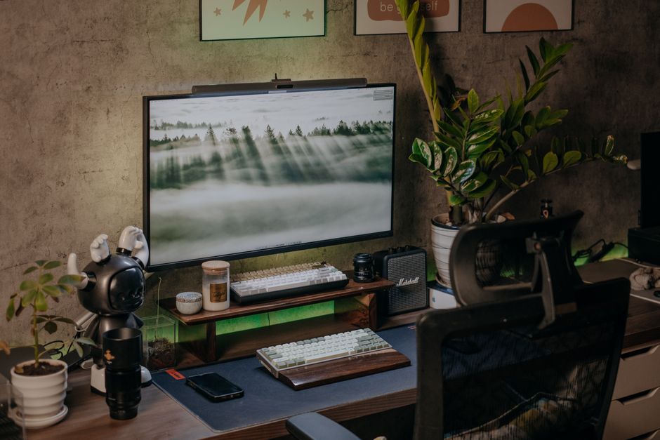 Stylish home office with modern desk setup, monitor, plants, and ambient lighting.
