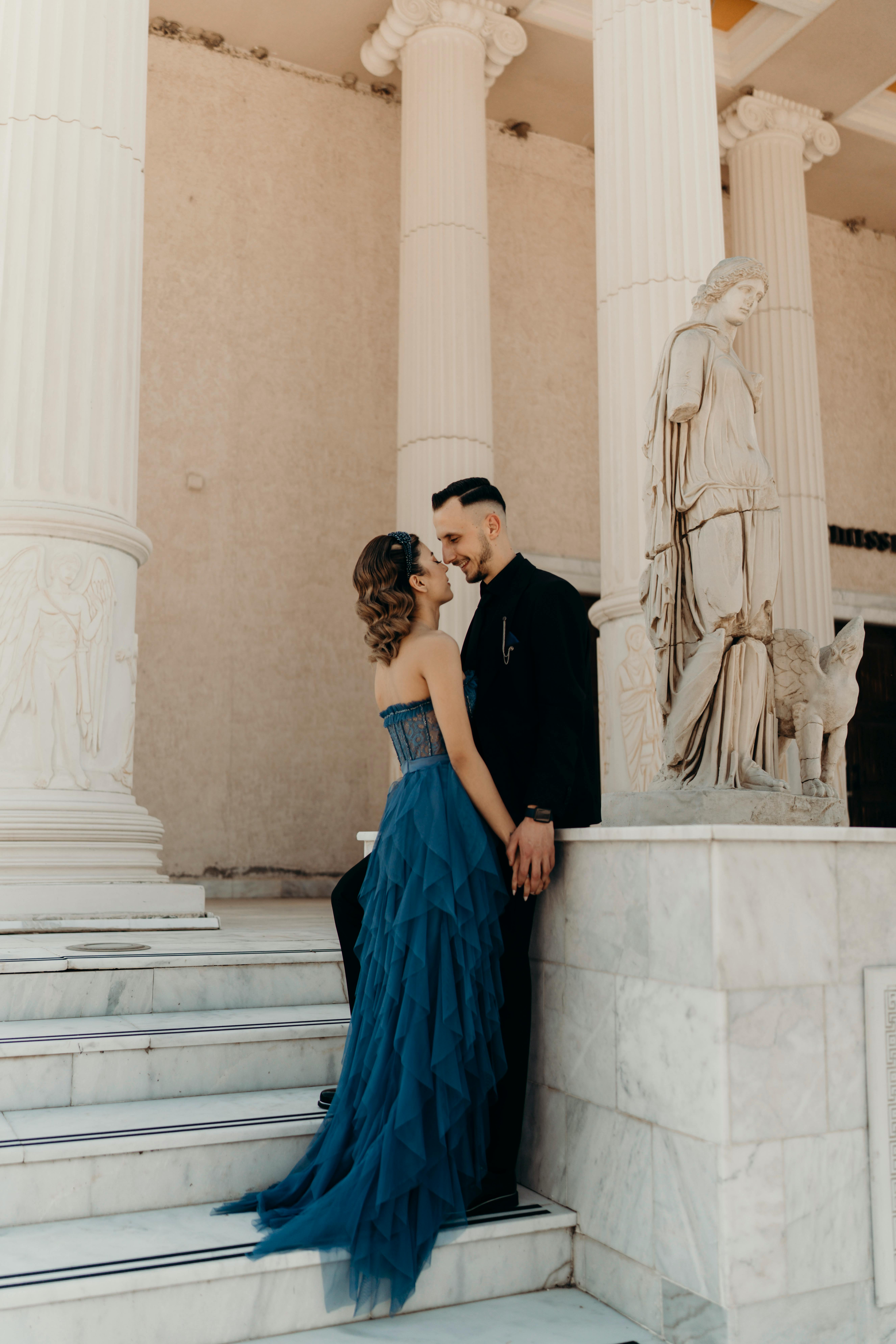 A fashionable couple in İzmir, Türkiye, posing elegantly near classical columns.