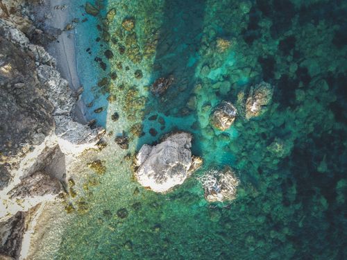 Free Top view of a rocky coastline with turquoise water, showcasing natural beauty and vibrant sea colors. Stock Photo